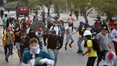 Grupos de jóvenes se enfrentaron a piedra con los uniformados cuando quisieron avanzar hacia el estadio. Foto AFP.