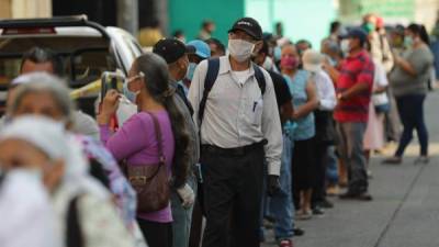 Salvadoreño hacen fila para ingresar a un banco en San Salvador. Las autoridades se quejan de que la población no acata las medidas de cuarentena.