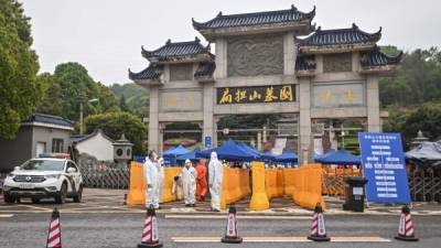 Personas en China se protegen con un traje especial para evitar el contagio del coronavirus. Foto: AFP