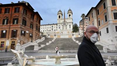 A man wearing a protection mask walks by the Spanish Steps at a deserted Piazza di Spagna in central Rome on March 12, 2020, as Italy shut all stores except for pharmacies and food shops in a desperate bid to halt the spread of a coronavirus. (Photo by Alberto PIZZOLI / AFP)