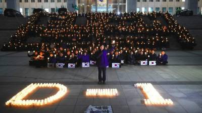 Parlamentarios de la oposición coreana sostienen velas en protesta contra la presidenta Park Geun-hye.