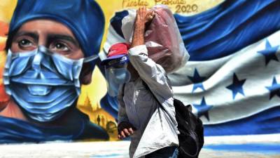 Un hombre transita frente a un mural que representa a un trabajador de la salud este lunes en Tegucigalpa. Tras casi seis meses de paralizado por la epidemia, el sector de transporte de pasajeros comienza a reactivarse.