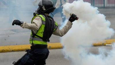 A riot policeman hurls a tear gas canister at opposition activists during a protest against President Nicolas Maduro, in Caracas on May 8, 2017.Venezuela's opposition mobilized Monday in fresh street protests against President Nicolas Maduro's efforts to reform the constitution in a deadly political crisis. Supporters of the opposition Democratic Unity Roundtable (MUD) gathered in eastern Caracas to march to the education ministry under the slogan 'No to the dictatorship.' / AFP PHOTO / FEDERICO PARRA