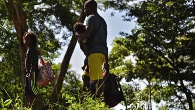 Un hombre migrante africano y sus hijos permanecen al costado de una carretera después de pasar por un 'cruce ciego' de Nicaragua a Honduras en su camino a los Estados Unidos, en Guasaule, Honduras, el 16 de noviembre de 2019.