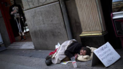 A man from Portugal sleeps in the street in Madrid, Spain, Friday, Oct. 26, 2012. Organizations such as the Spanish Red Cross and the Catholic Church charity organization Caritas say unemployment and the austerity measures are leaving tens of thousands of people in need of food and financial help. The banner reads in spanish 'I am Portuguese, I need help to go back to my country'. (AP Photo/Emilio Morenatti)