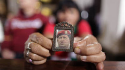 A woman holds an image of Venezuela's President Hugo Chavez as people gather to pray for him at a church in Caracas, Venezuela, Monday, Dec. 31, 2012. Venezuela's President Hugo Chavez is confronting 'new complications' due to a respiratory infection nearly three weeks after undergoing cancer surgery, his Vice President Nicolas Maduro said Sunday evening in Cuba as he visited the ailing leader for the first time since his operation. (AP Photo/Ariana Cubillos)