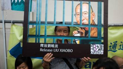 Activistas de la Alianza de Hong Kong en Apoyo de Movimientos Democráticos Patrióticos en China, muestran fotografías de chinos disidentes y del premio Nobel de la Paz Liu Xiaobo durante una marcha en Hong Kong, China, hoy, 10 de julio. EFE