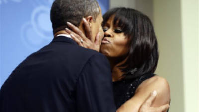 President Barack Obama kisses first lady Michelle Obama as they speak to supporters and donors at an inaugural reception for the 57th Presidential Inauguration at The National Building Museum in Washington, Sunday, Jan. 20, 2013. (AP Photo/Charles Dharapak)
