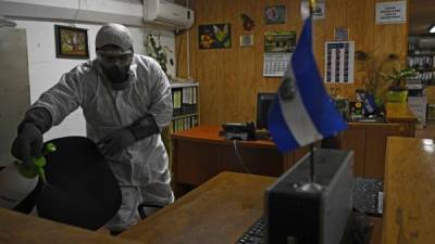 Un trabajador municipal desinfecta el edificio del alcalde municipal de San Salvador. AFP
