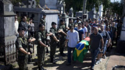 Soldiers stand, left, as relatives and friends carry the coffin during the burial of fire victim soldier Leonardo Machado, at a cemetery in Santa Maria city, Rio Grande do Sul state, Brazil, Monday, Jan. 28, 2013. A fast-moving fire roared through the crowded, windowless Kiss nightclub in southern Brazil early Sunday, within seconds filling the space with flames and smoke that killed more than 230 panicked partygoers who gasped for breath and fought in a stampede to escape. An early investigation into the tragedy revealed that security guards briefly prevented partygoers from leaving through the sole exit and the bodies later heaped inside that doorway slowed firefighters trying to get in (AP Photo/Felipe Dana)