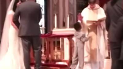 El momento donde el inocente niño se acerca al sacerdote quien dirige el acto nupcial, para chocar la mano. Foto YouTube