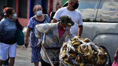 People wear face masks against the spread of the new coronavirus at a street market in Tegucigalpa, on March 22, 2020. - Authorities have confirmed 26 cases of COVID-19 in the country so far. (Photo by ORLANDO SIERRA / AFP)