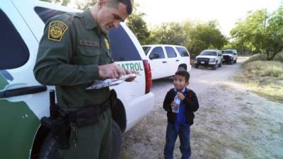 Un agente de la patrulla de fronteras lee la partida de nacimiento de un niño hondureño que intentaba cruzar la frontera de Estados Unidos en 2014. Foto de AP.