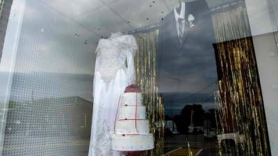 Un vestido de novia y un traje de novio son expuestos en una tiena de Millinocket, el pueblito de Maine donde murieron 7 personas y se infectaron casi otras 200 por asistir a una boda./AFP.