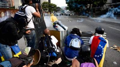 TOPSHOT - Demonstrators clash with police during a march against Venezuelan President Nicolas Maduro, in Caracas on April 19, 2017.Venezuelans took to the streets Wednesday for massive demonstrations for and against President Nicolas Maduro, whose push to tighten his grip on power has triggered deadly unrest that has escalated the country's political and economic crisis. / AFP PHOTO / FEDERICO PARRA