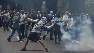 Manifestantes opositores se enfrentan a la policía que intenta reprimir una protesta en Caracas.