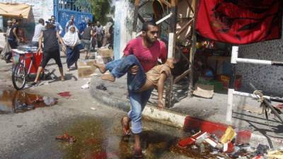 Un hombre corre con un niño herido tras un ataque israelí ayer en Gaza. La OnU alertó de un desastre sanitario en la zona.
