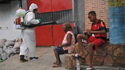 A volunteer disinfects an area inside Babilonia favela, Rio de Janeiro on April 18, 2020. - Neighbours of the Santa Marta favela are helping to disinfect and train volunteers in Babilonia favela to fight against COVID-19 coronavirus. Favela residents are taking matters into their own hands and providing services during the pandemic because they claim that they are not being assisted by the government. (Photo by CARL DE SOUZA / AFP)