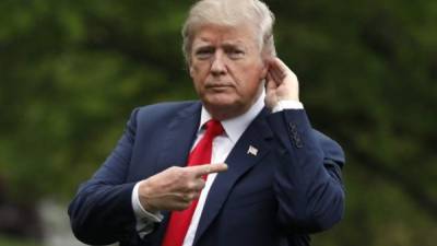 El presidente de EE. UU., Donald Trump, hace un gesto hacia los medios de comunicación mientras camina por South Lawn a su regreso a la Casa Blanca en Washington desde Cleveland.