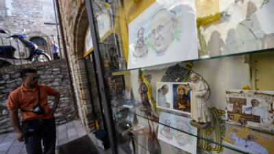 A man looks at portraits of Pope Francis in a tourist shop in the center of Assisi on October, 3, 2013 on the eve of the visit of the pontiff. AFP PHOTO / ANDREAS SOLARO