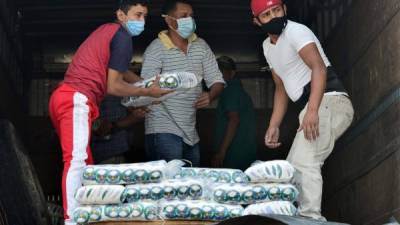Los trabajadores cargan productos alimenticios en un camión en Tegucigalpa en medio de la pandemia de coronavirus COVID-19. / AFP / Orlando SIERRA