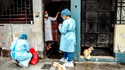 Un trabajador de salud peruano se prepara para realizar una prueba de covid-19 a una mujer en su casa.