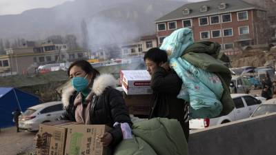 Los residentes llevan ayuda después del terremoto, durante una gira de prensa en Dahejia, en la provincia de Gansu, China, 20 de diciembre de 2023.