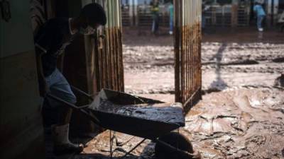 Un hombre intenta limpiar su casa anegada por el lodo. EFE.