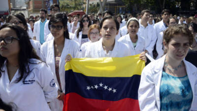 A woman demonstrates with a sign reading 'Friend: you who defend a corrupt government, get attached to the constitution', in front of a line of riot police outside the Venezuelan Navy command headquarters at San Bernardino neighborhood in Caracas on May 4, 2019. - Venezuelan President Nicolas Maduro called on the armed forces to be 'ready' in the event of a US military offensive against the South American country, in a speech to troops on Saturday. His speech at a military base came as opposition leader Juan Guaido rallied his supporters in a new day of protests to press the armed forces to support his bid to dislodge Maduro. (Photo by Juan BARRETO / AFP)