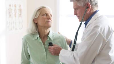 A doctor listens to a senior woman patient's heart beat. See my portfolio for more in this series.