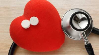 Red heart, stethoscope and pills on wooden background