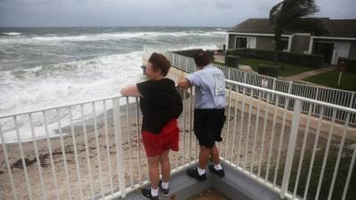 Residentes de Jupiter, Florida observan el oleaje en la víspera de la llegada con toda su fuerza del huracán Matthew.
