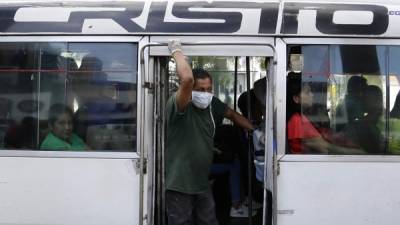 Un hombre viaja en un autobús usando tapacobas el pasado lunes en San Salvador. EFE