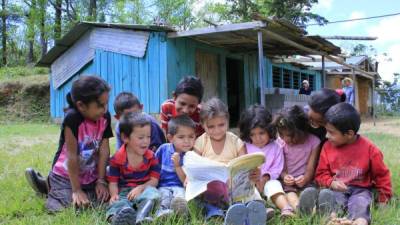 Escolares leen un libro afuera de su inservible centro educativo en Las Cruces. Foto: Cristina Santos