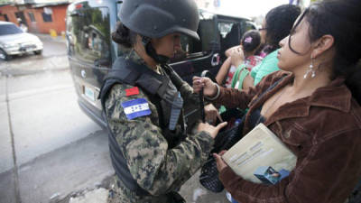 Un miembro de la Policía Militar requisa a un grupo de mujeres hoy, lunes 14 de octubre de 2013, en la colonia La Pradera de Tegucigalpa (Honduras). EFE