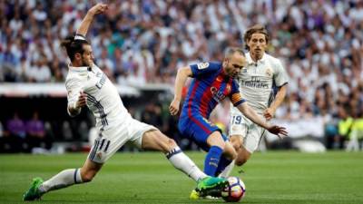 El centrocampista del Barcelona Andrés Iniesta (c) pelea un balón con el centrocampista galés del Real Madrid, Gareth Bale (i) en un partido de Liga. EFE/Archivo