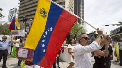 En la imagen, un exiliado venezolano despliega una bandera de su país en una calle de Miami. EFE/Archivo