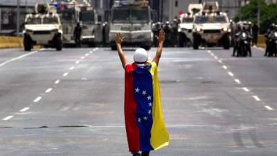 Un hombre permanece en frente de los vehículos de la Guardia Nacional Bolivariana (GNB) durante una manifestación opositora en Venezuela. EFE/Archivo