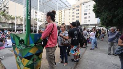 Varias personas hacen fila para recargar la batería de sus teléfonos móviles en un punto público durante el apagón eléctrico en Caracas (Venezuela). EFE