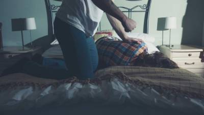 A man is beating his wife on a bed
