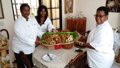 Beatriz Beaumont, su hija Angie Colbourne y la chef Wanda Bodden muestran platillos.