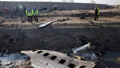 Miembros de los servicios de emergencia observan parte del fuselaje del Boeing 737 de la compañía ucraniana UIA que se estrelló el 8 de enero de 2020 en Teherán (Israel). EFE/Abedin Taherkenareh