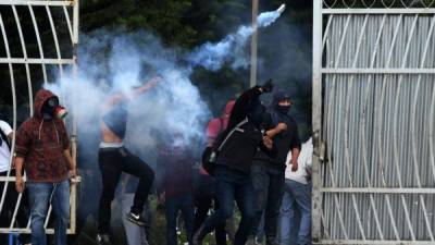 Estudiantes de la Universidad Nacional Autónoma de Honduras (UNAH) se enfrentan con la policía antidisturbios durante una protesta contra la reelección del presidente Juan Orlando Hernández.