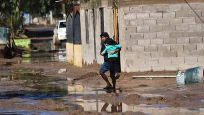 Un hombre cruza con su hija por una calle inundada debido a un temporal de lluvia en Chile. EFE/Archivo