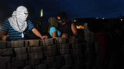 Manifestantes nicaragüenses se resguardan detrás de una barricada en Managua.