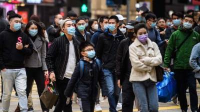 TOPSHOT - Pedestrians wearing face masks cross a road during a Lunar New Year of the Rat public holiday in Hong Kong on January 27, 2020, as a preventative measure following a coronavirus outbreak which began in the Chinese city of Wuhan. (Photo by Anthony WALLACE / AFP) (Photo by ANTHONY WALLACE/AFP via Getty Images)