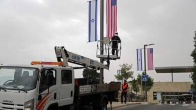 Un trabajador instala decoraciones de banderas israelíes y estadounidenses frente al consulado de EE. UU. En Jerusalén. THOMAS COEX / AFP