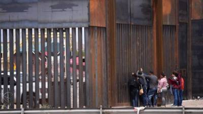 Migrantes centroamericanos se asoman en por el muro fronterizo, para entregarse a las autoridades migratoria estadounidenses, en el tramo de Puente Nuevo, en Ciudad Juárez (México). EFE/ Rey R. Jauregui/Archivo
