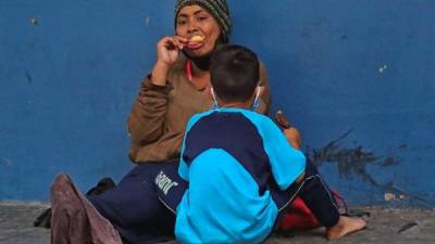 Una mujer y un niño permanecen sentados en una calle en la que piden diner este miércoles en Tegucigalpa (Honduras). EFE/ Gustavo Amador