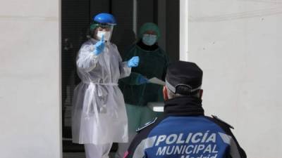 Una trabajadora de la salud haciendo un gesto a un policía municipal durante las pruebas de detección del coronavirus COVID-19 en Madrir. AFP